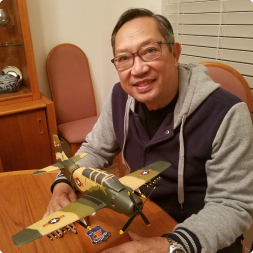 gallery image of satisfied customer holding a camoflauged aircraft model on a wooden mount stand