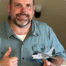 gallery image of satisfied customer with two thumbs up holding a miniature aircraft model