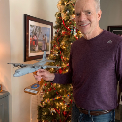 gallery image of satisfied customer holding an aircraft model on wooden stand in front of chrismas tree