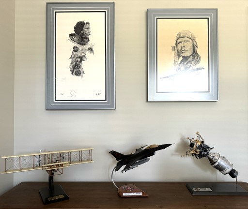 Display with framed portraits above Wraith F‑16 model on wooden stand