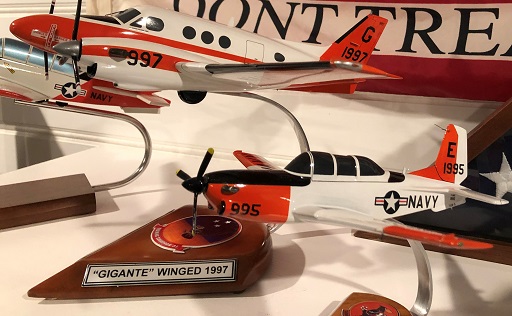 T‑44A and T‑34C mini aircraft models on curved metal stands with Navy markings displayed side by side