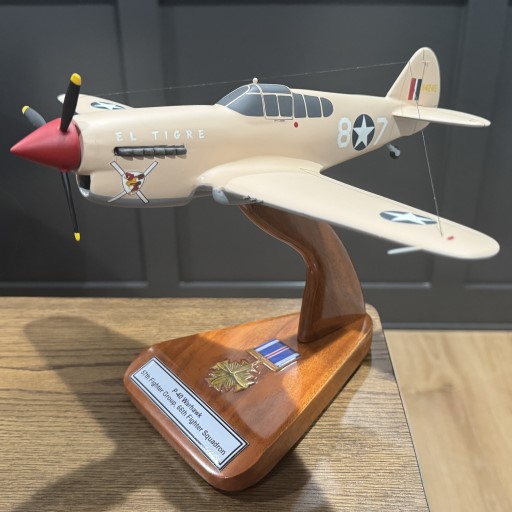 WWII P‑40 Warhawk model on wooden stand with desert camouflage, “EL TIGRE” name, star insignia, and tail markings