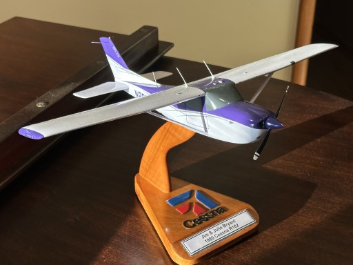 Custom wooden Cessna R182 aircraft model (N8051B) on display stand with realistic paintwork, propeller, landing gear, and antenna