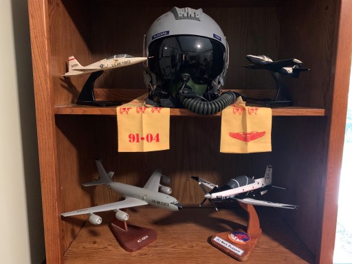 Aircraft models and a pilot's helmet are displayed on a wooden shelf
