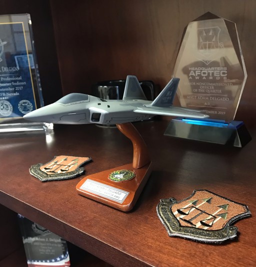 Wooden shelf displaying an aircraft model with military awards and patches
