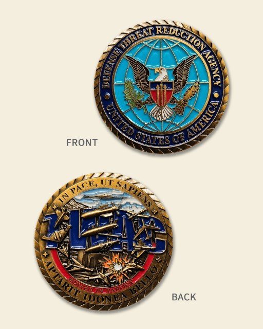 Defense Threat Reduction Agency TWAC Bombs in Target challenge coin featuring eagle seal, aircraft, explosions, Latin motto, and multicolor enamel design.