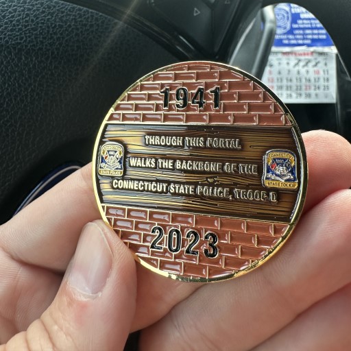Front of Connecticut State Police Troop D challenge coin showing dedication to officers and K9s.