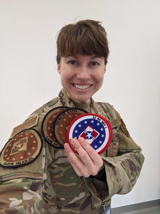 Customer in uniform holding 52 OG Det 1 Poland patch and OCP version