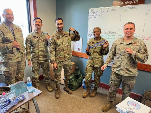 Five uniformed personnel pose indoors holding lanyards