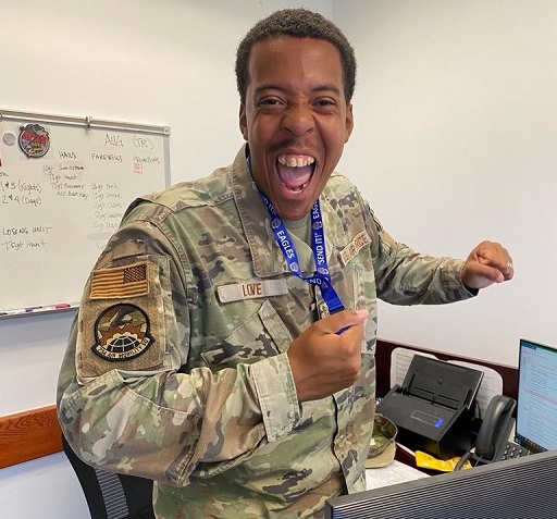 Airman in uniform poses indoors wearing 734 AMS lanyard with expressive gesture
