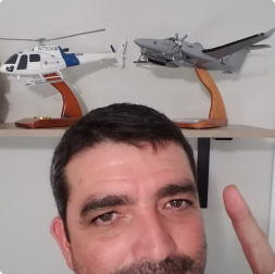 gallery image of satisfied customer pointig to two models above his head - one of a military airplane, another of a civilian helicopter