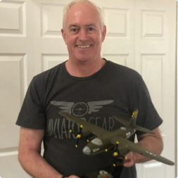 gallery image of satisfied customer wearing an aviator gear shirt holding a large aircraft model