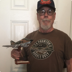 gallery image of very satisfied customer holding a fighter aircraft model on wooden stand