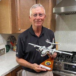 gallery image of satisfied customer holding a dual engine aircraft model on wooden stand in kitchen